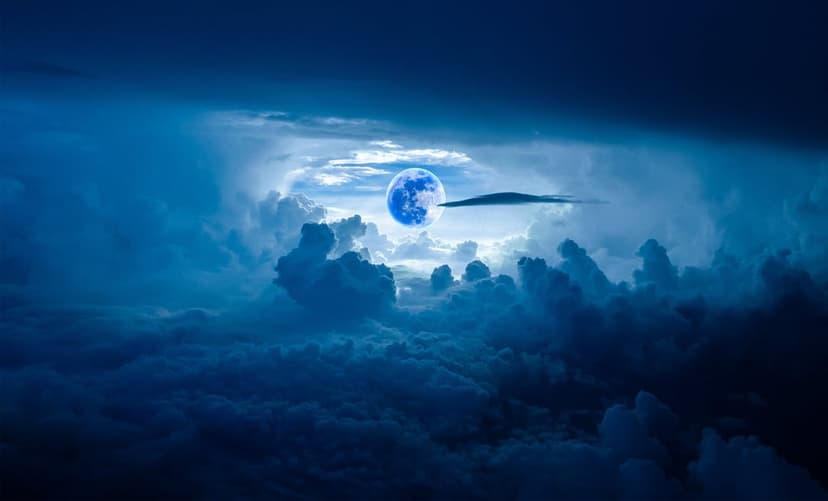 Bright blue moon glowing through heavy dark storm clouds with a high contrast celestial light effect.