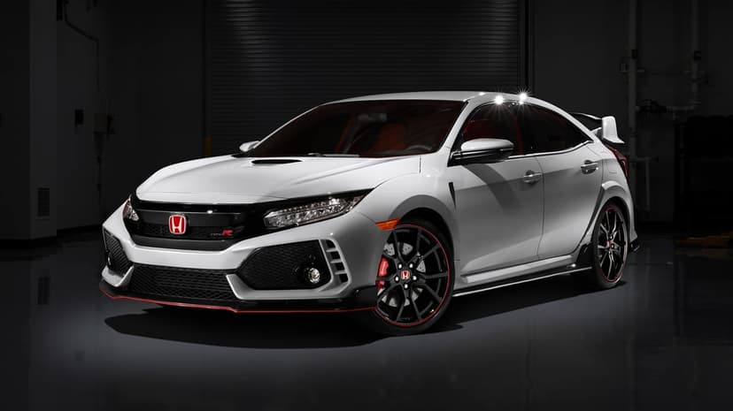 White Honda Civic Type R parked in a dark studio with dramatic lighting and red accents on wheels and trim.