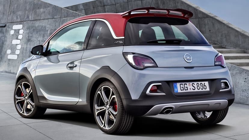 Silver Opel Adam S with a red roof parked against a concrete wall under soft daylight for desktop use.