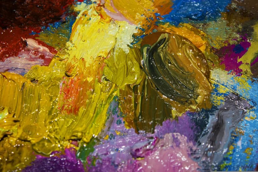 Thick streaks of yellow, green, and blue oil paint blend together in a glossy macro impasto texture.