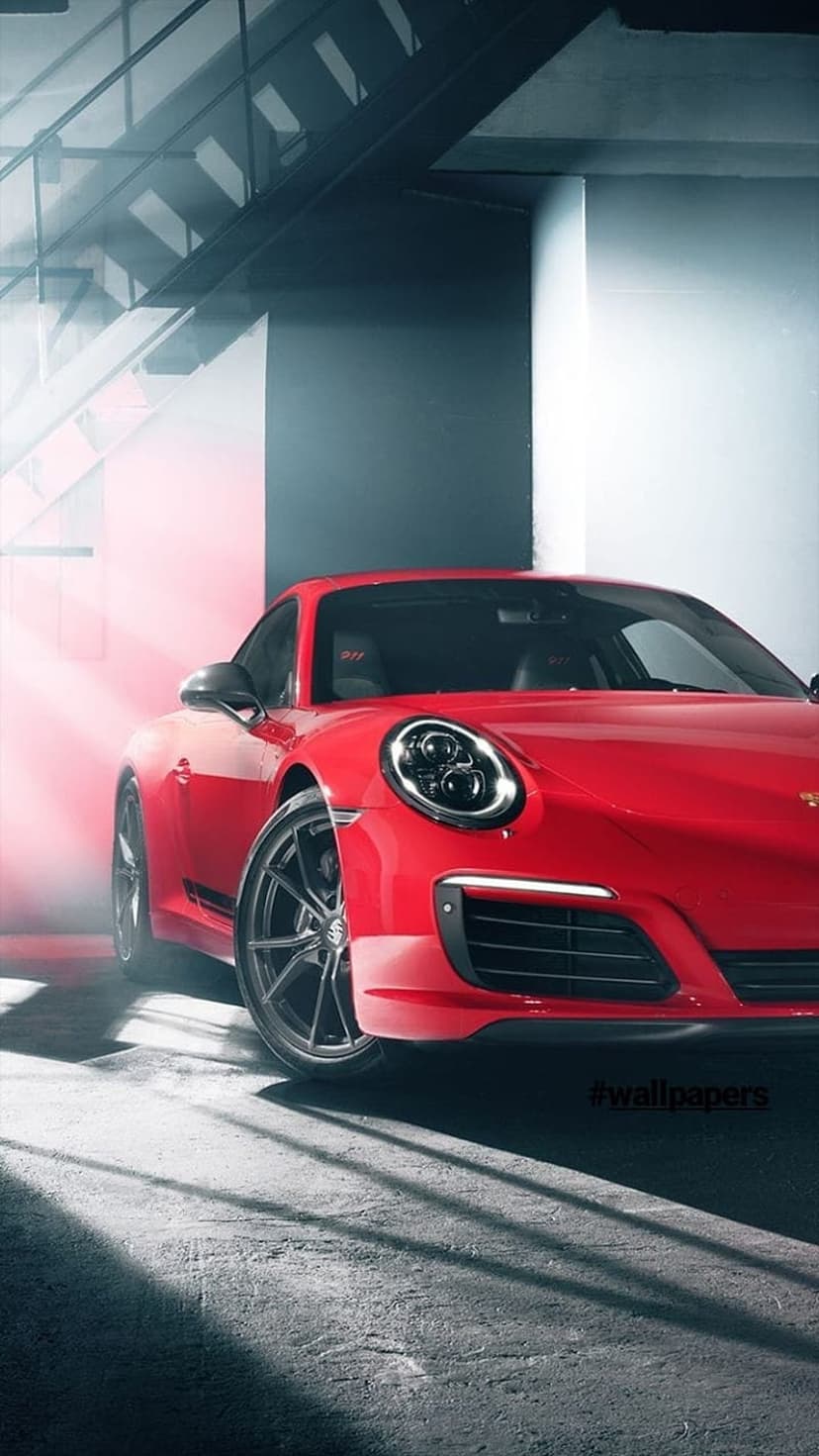 Red Porsche 911 sports car parked beneath a concrete staircase with high-contrast cinematic shafts of light.