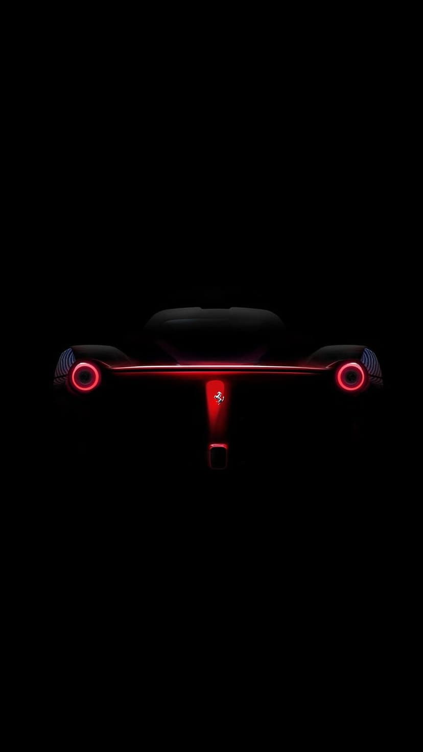 Ferrari LED tail lights illuminate a dark silhouette, highlighting the rear aerodynamic curves and logo.