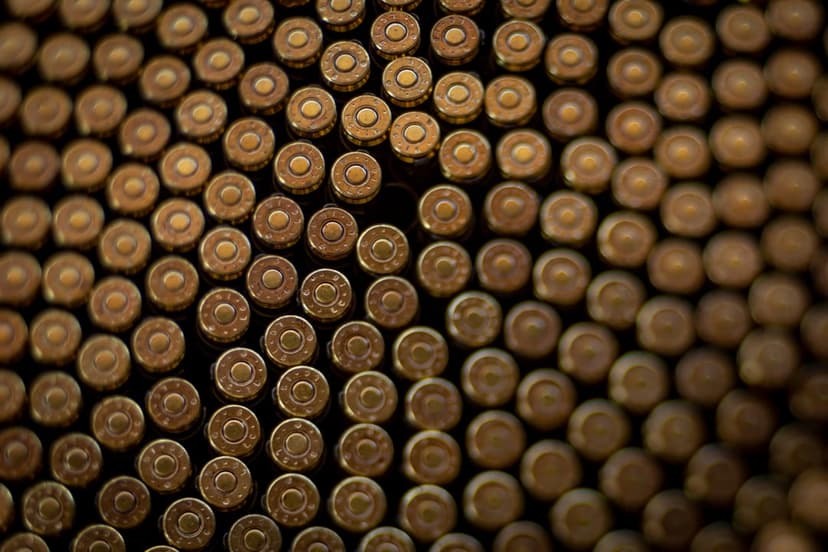 Polished brass bullets stacked in tight rows with a shallow depth of field and soft metallic reflections.
