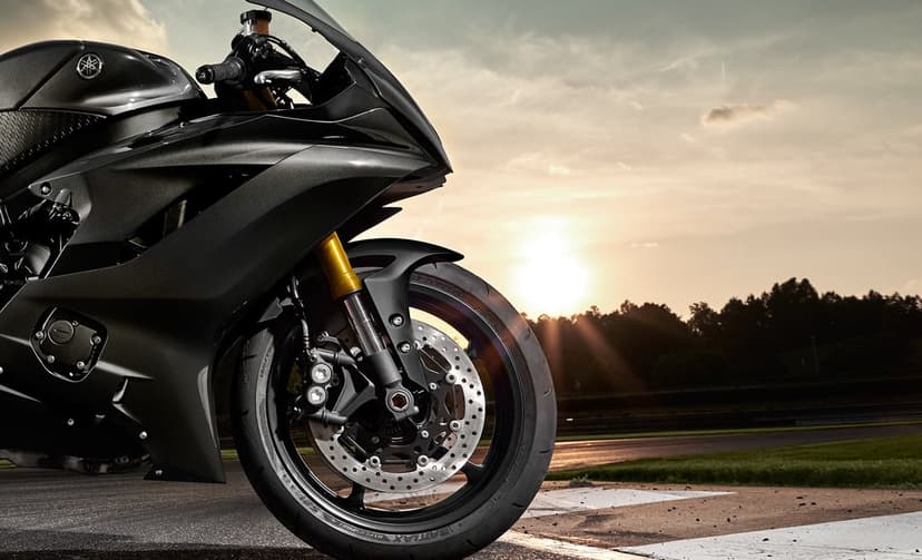 Dark matte sportbike on a racetrack during a golden sunset with sunbeams hitting the front wheel and brakes.