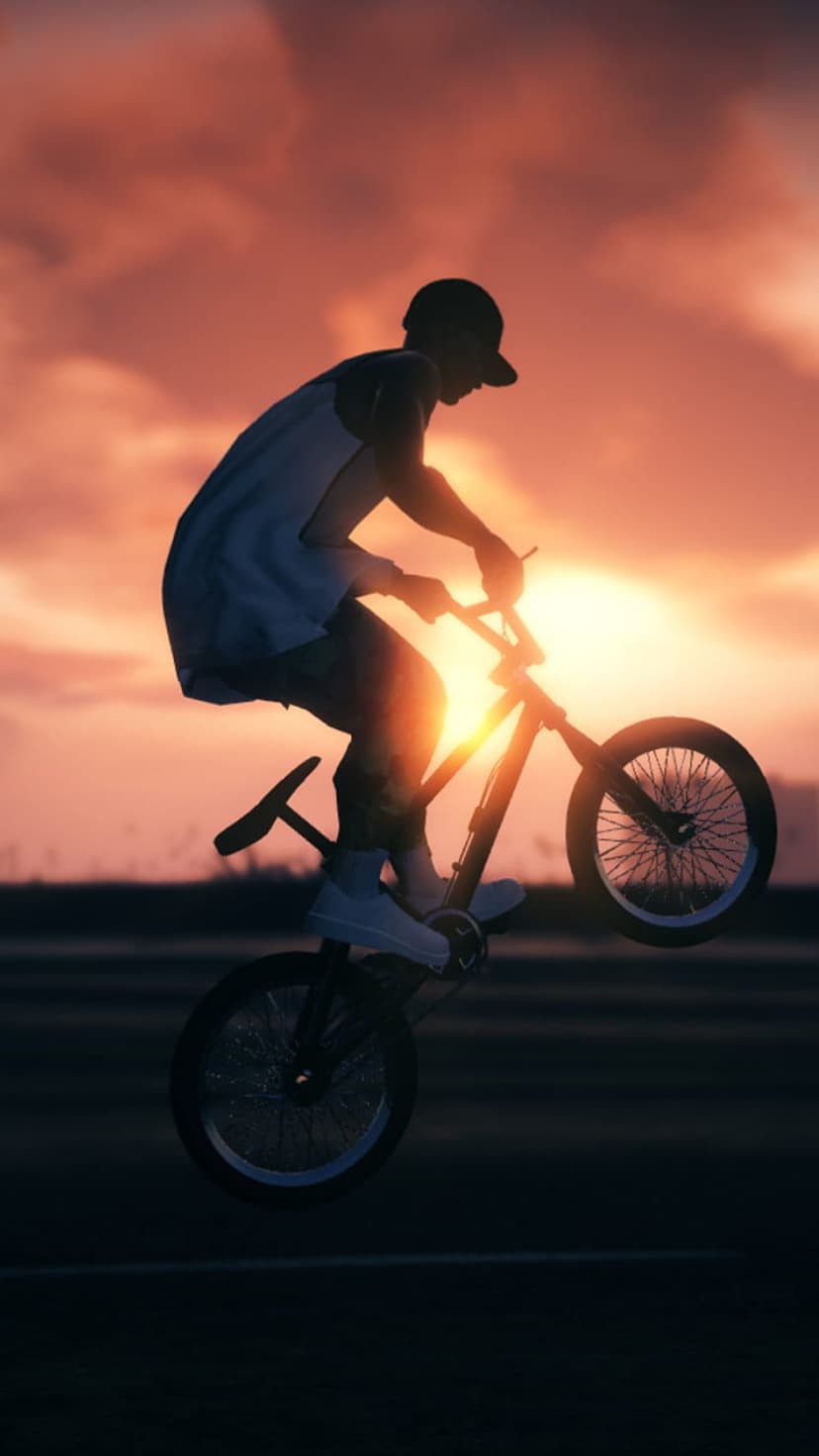 BMX cyclist silhouetted mid-air against a vibrant orange and pink sunset sky while performing a freestyle trick.