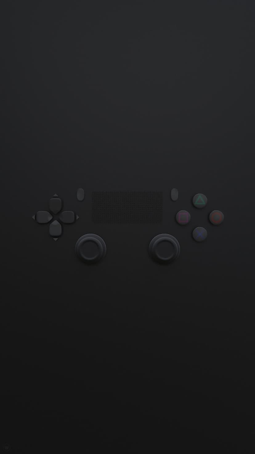 Black gaming controller with colorful geometric buttons and dual analog sticks resting on a dark surface.