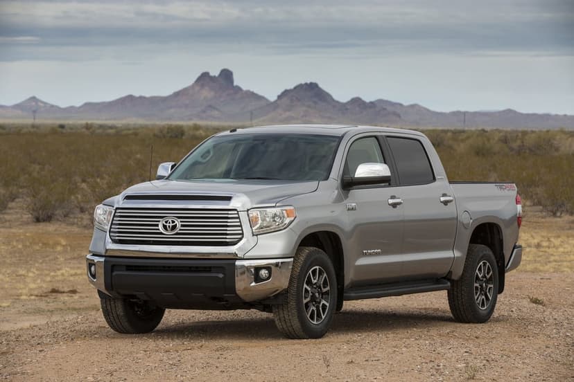 Silver Toyota Tundra pickup truck parked on a dirt trail with desert mountains and a cloudy sky in the background.