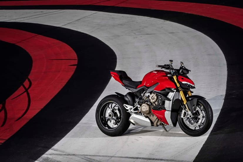 Red Ducati Streetfighter motorcycle on a curved racetrack with black, white, and red stripes under dramatic light.