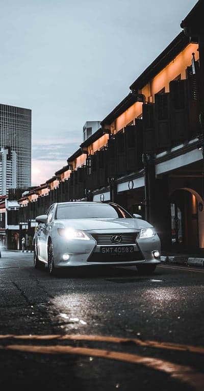 Lexus on Wet Street with Cityscape at Dusk