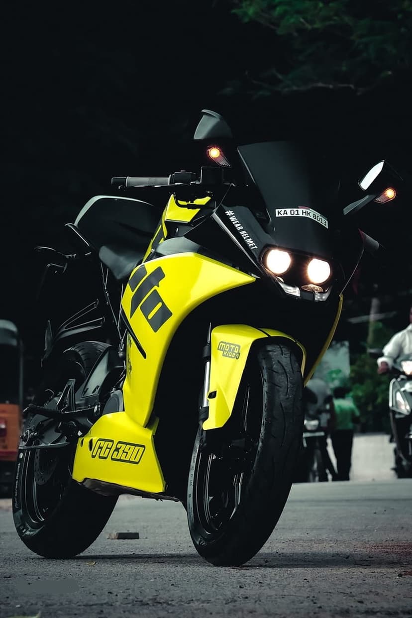 Yellow and black FC 390 motorcycle with twin headlights viewed from a low front angle against a blurred background.