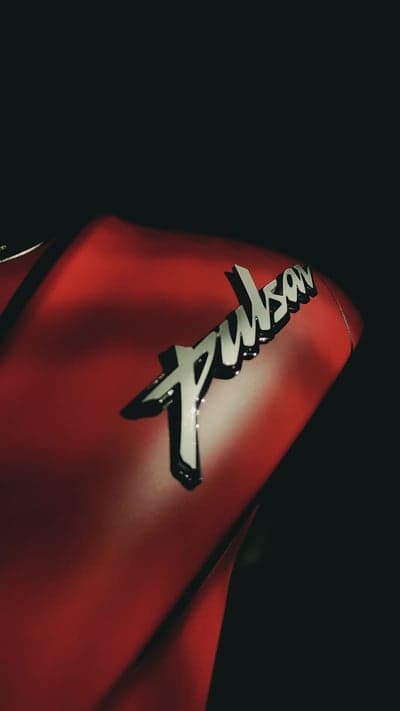 Pulsar Logo Close-up on Red Motorcycle Tank Phone Wallpaper