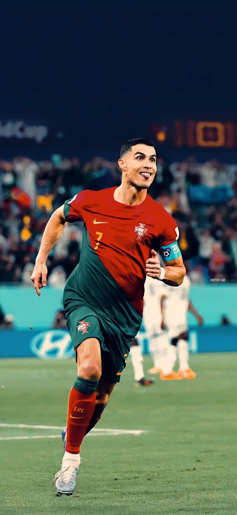 Cristiano Ronaldo in a red Portugal jersey celebrates on a grass field with stadium lights blurred behind him.