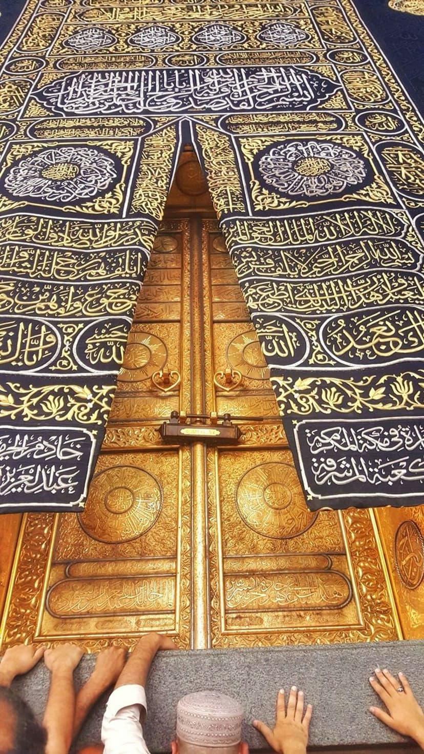 Golden Kaaba doors and black Kiswah cloth with intricate Arabic calligraphy embroidery and religious metalwork.