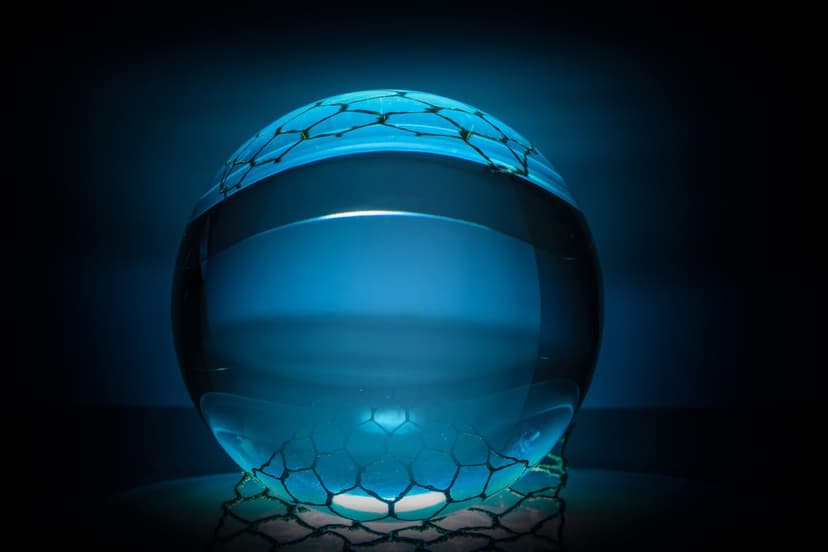 Luminous blue orb filled with radiant liquid rests on a dark hexagonal base with sharp geometric patterns.