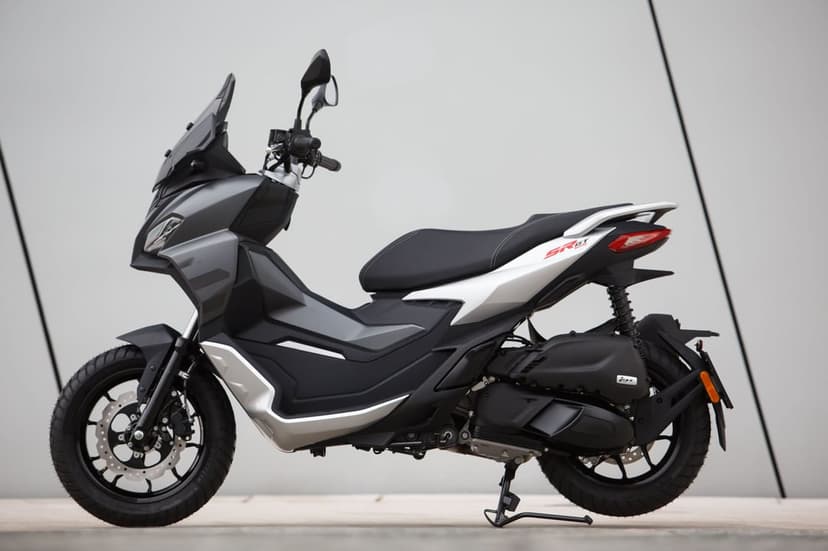 Aprilia SR GT 125 adventure scooter in gray and silver against a minimalist neutral wall background.