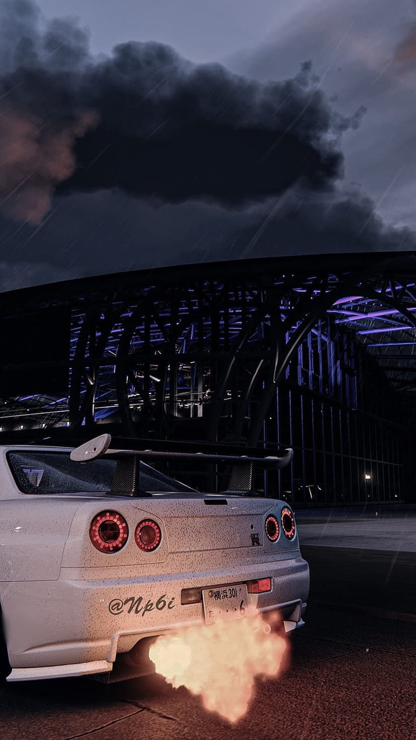White Nissan Skyline sports car emitting orange exhaust flames under a dark stormy sky near a lighted stadium.