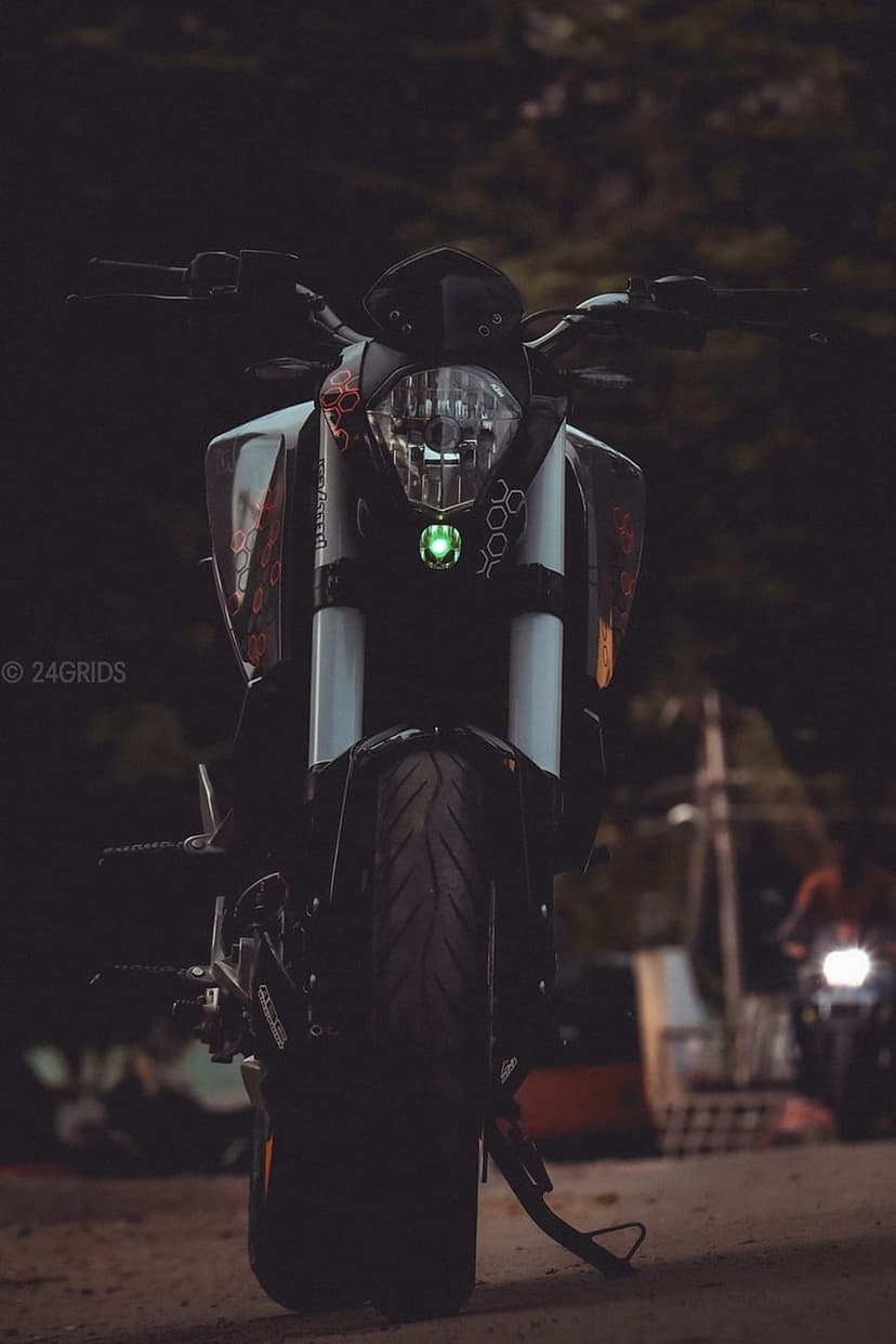 KTM Duke headlight assembly with a glowing green LED strip and sharp mechanical lines against a dark background.