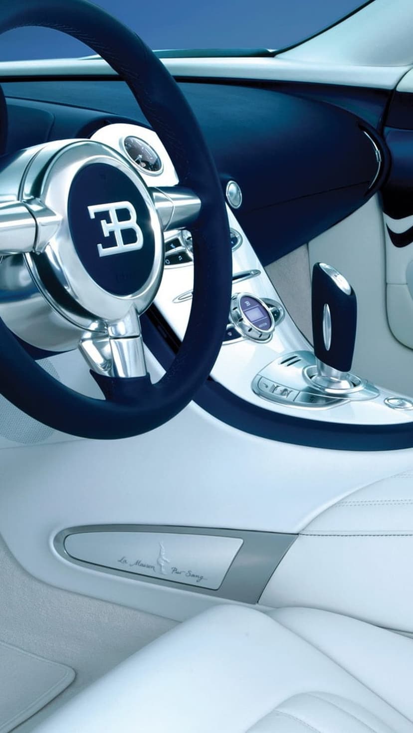 Bugatti Veyron steering wheel with EB logo and white leather gear shift in a luxury supercar cockpit.