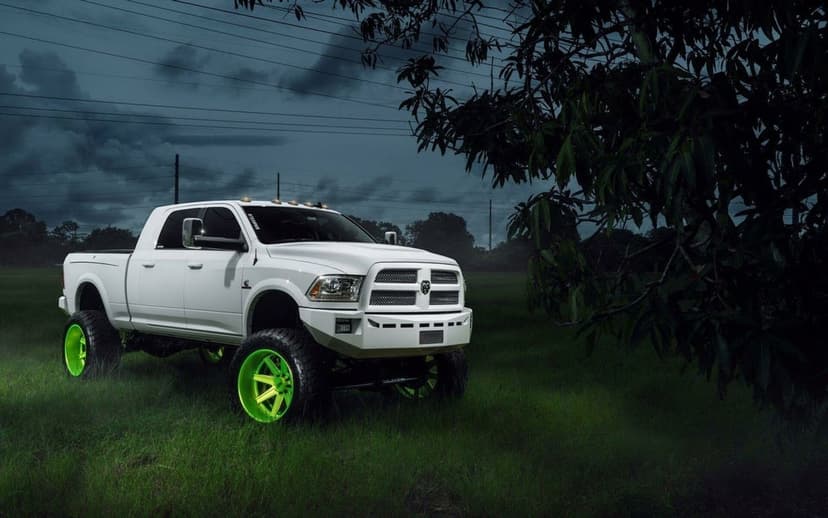 White lifted Dodge Ram truck with neon green wheels in a dark grassy field under a stormy twilight sky.