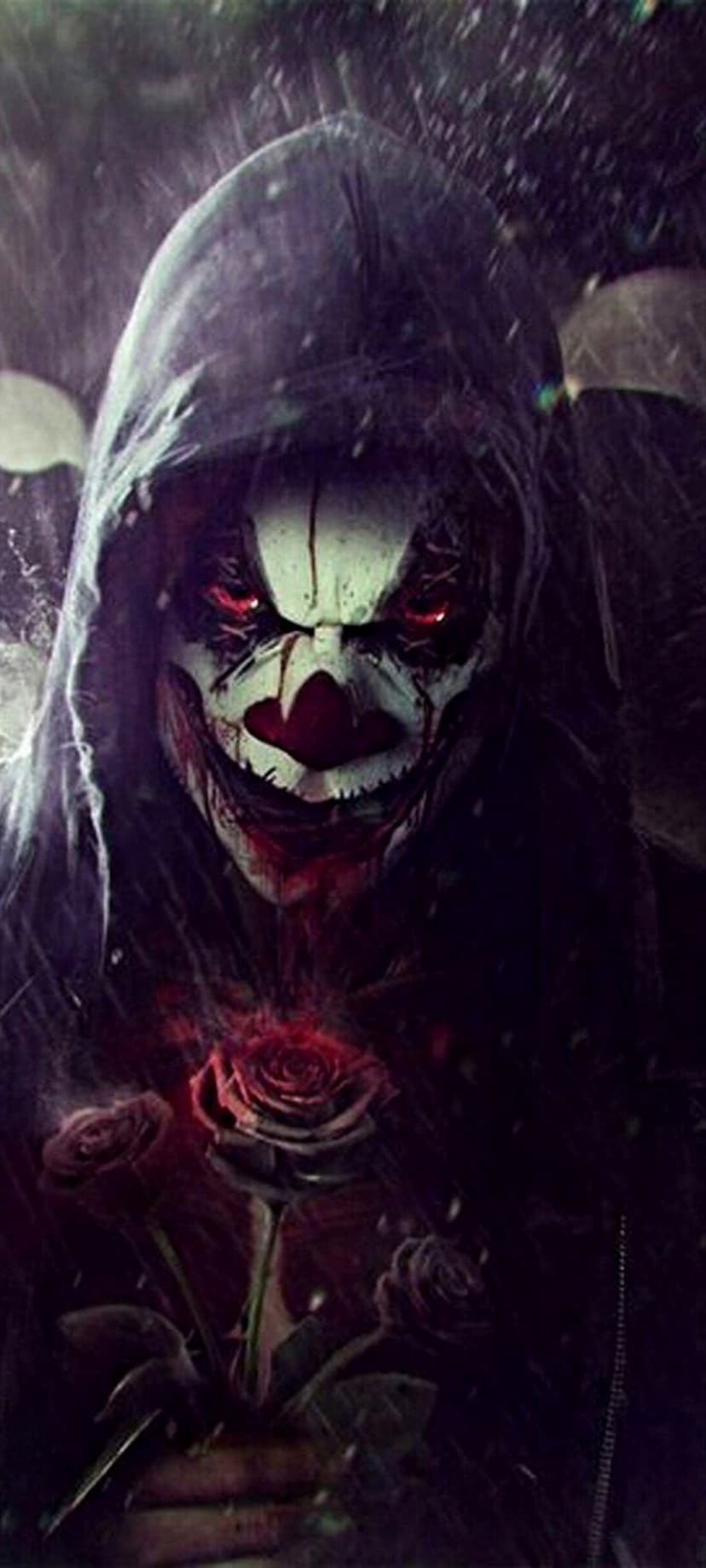 Sinister clown with glowing red eyes wears a dark hood while holding a wet red rose during a rainstorm.