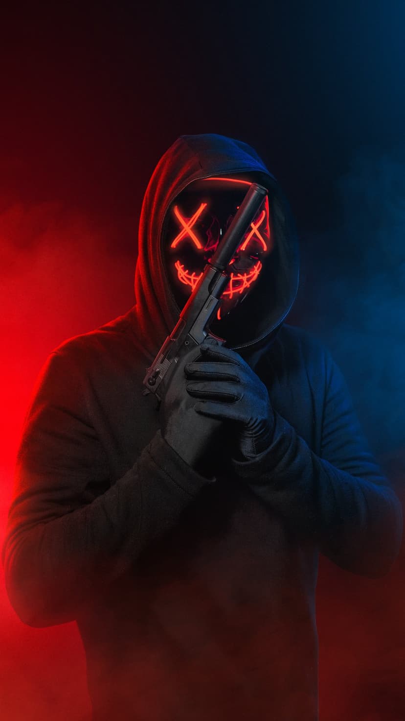 Person in a black hoodie wearing a red LED X mask and holding a gun against a red and blue gradient background.