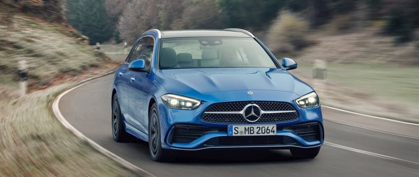 Blue Mercedes-Benz C-Class Estate driving on a winding road with motion-blurred trees in the background.