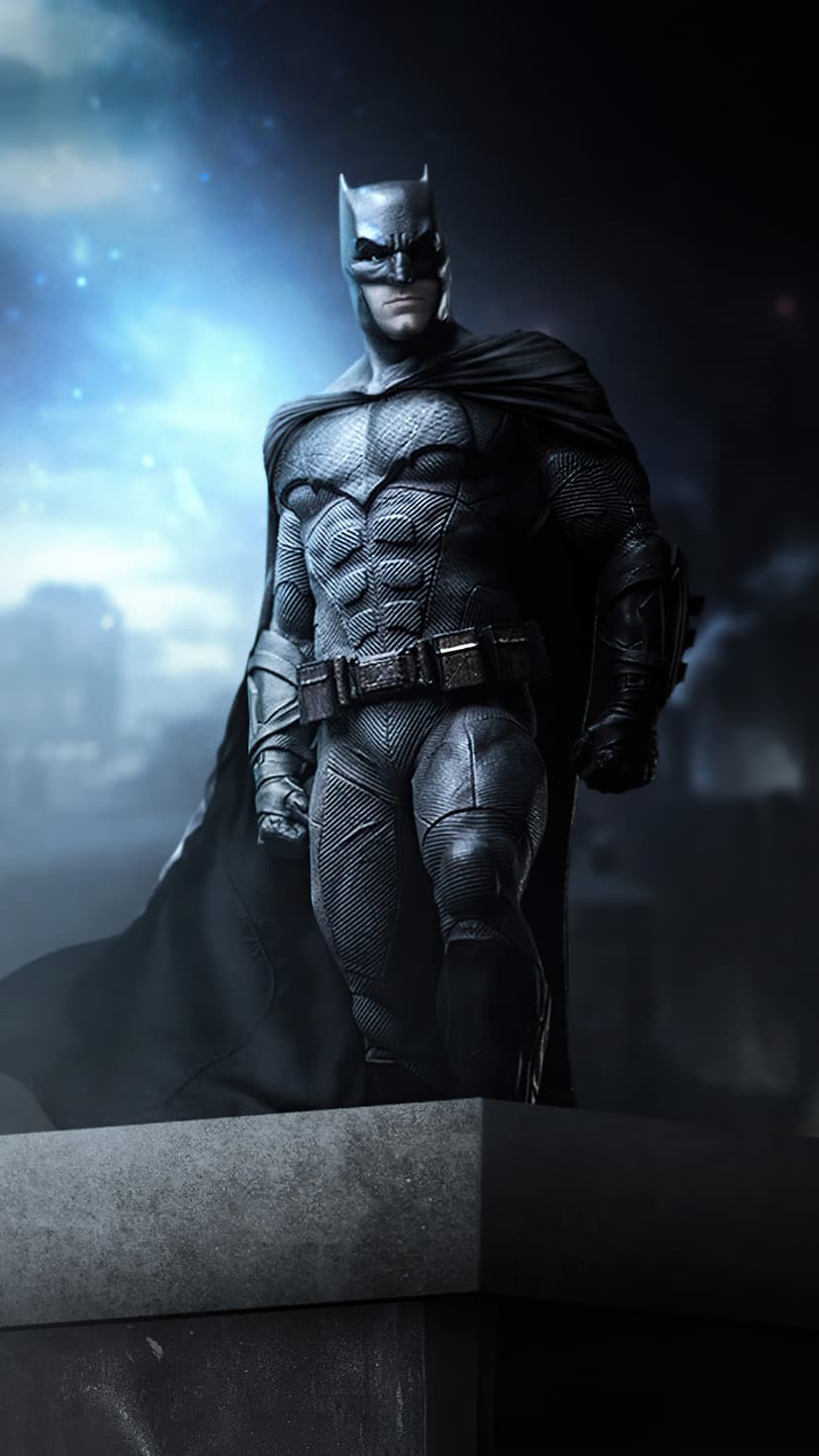 Batman stands on a stone ledge under a blue rim light against a dark cloudy sky with faint city lights.