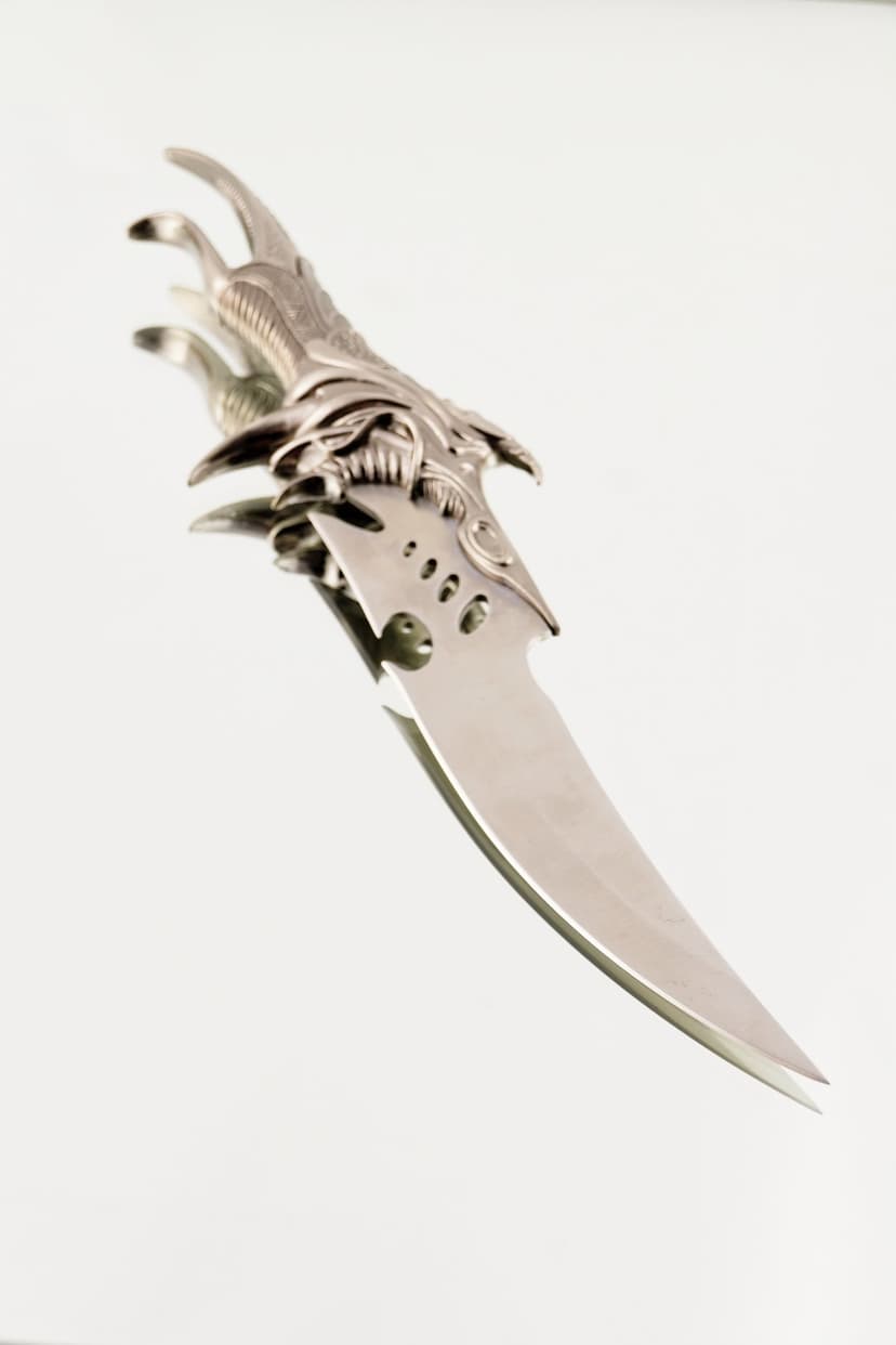 Dragon claw knife with jagged serrated steel edges and bone-textured hilt against a dark atmospheric backdrop.