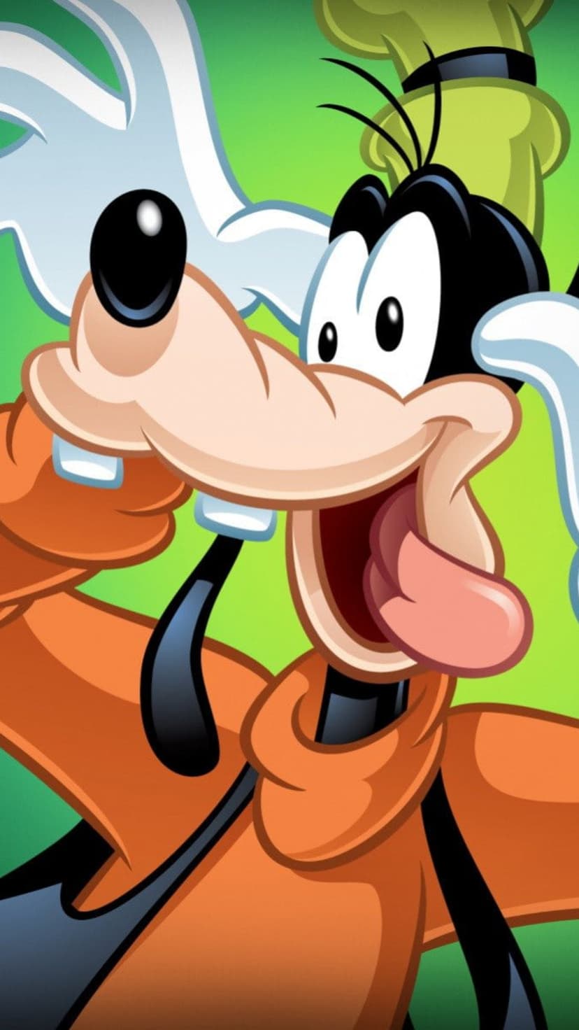 Goofy makes a silly face with his tongue out against a solid green background wearing an orange shirt.