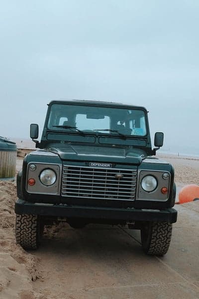 Classic Land Rover Defender parked on a sandy beach
