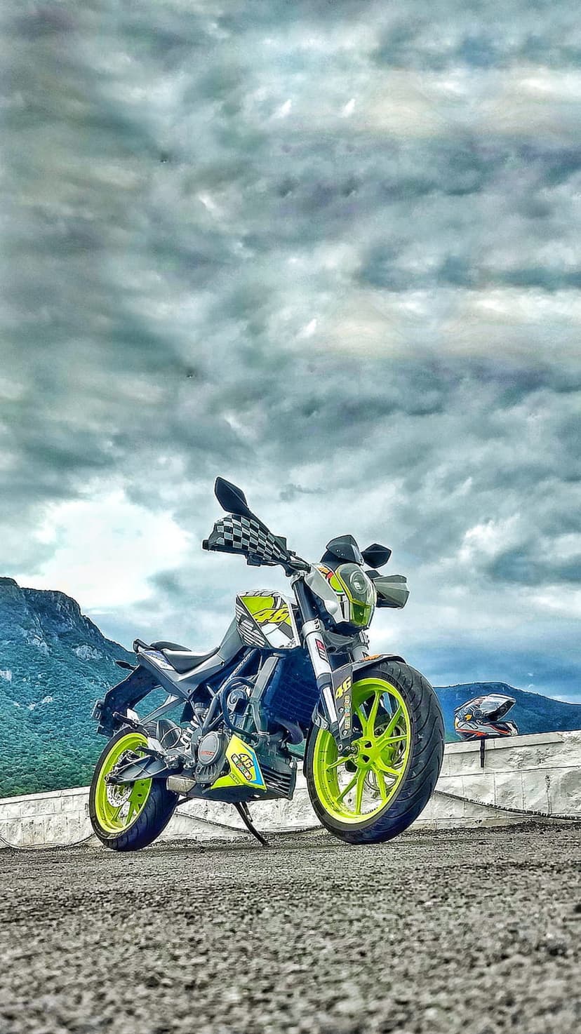 Neon green and white sports motorcycle parked on rocky ground beneath dark, dramatic storm clouds and a helmet.