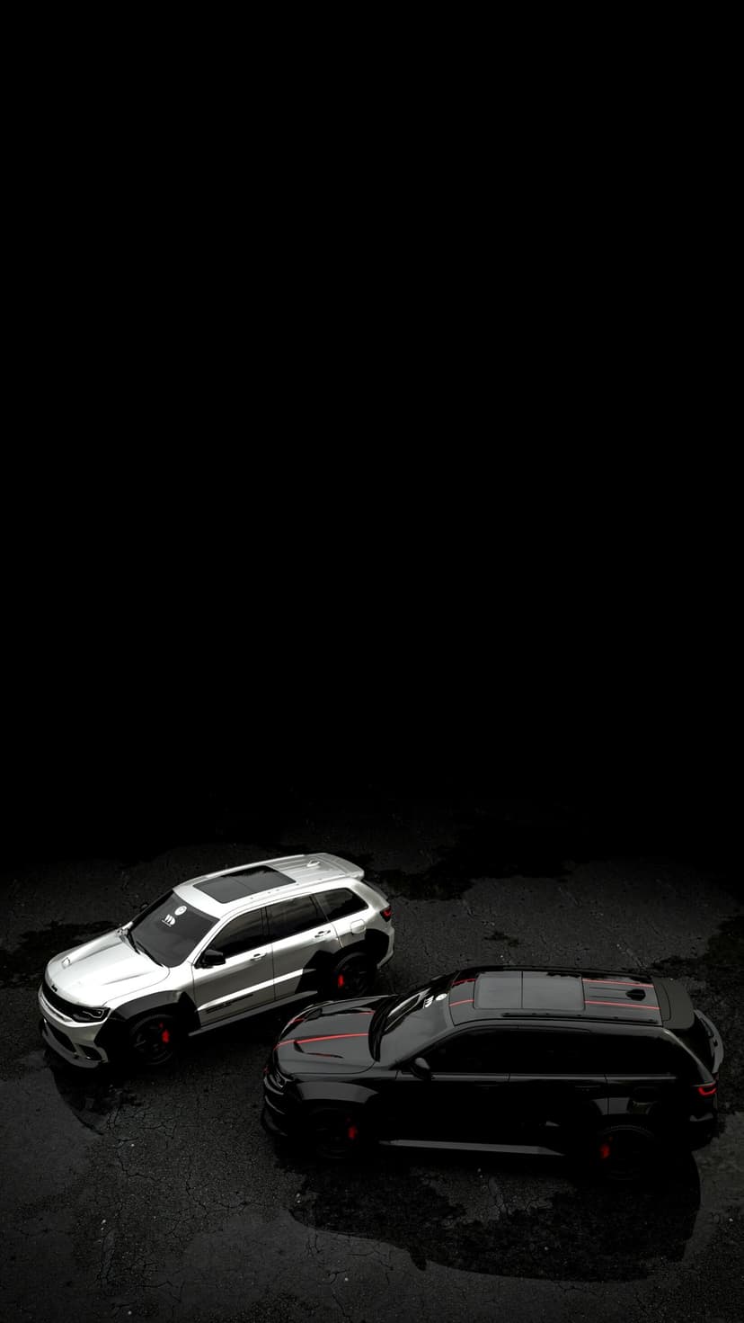 Silver and black SUVs parked on wet asphalt with mirror-like reflections under a dark, atmospheric sky.
