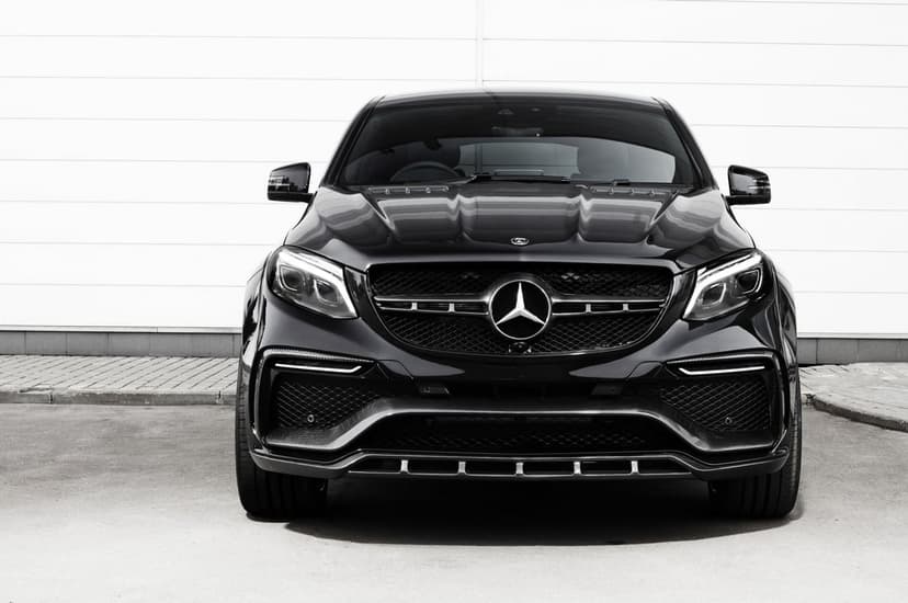 Front view of a sleek black Mercedes-Benz SUV with a detailed grille and logo against a white wall background.