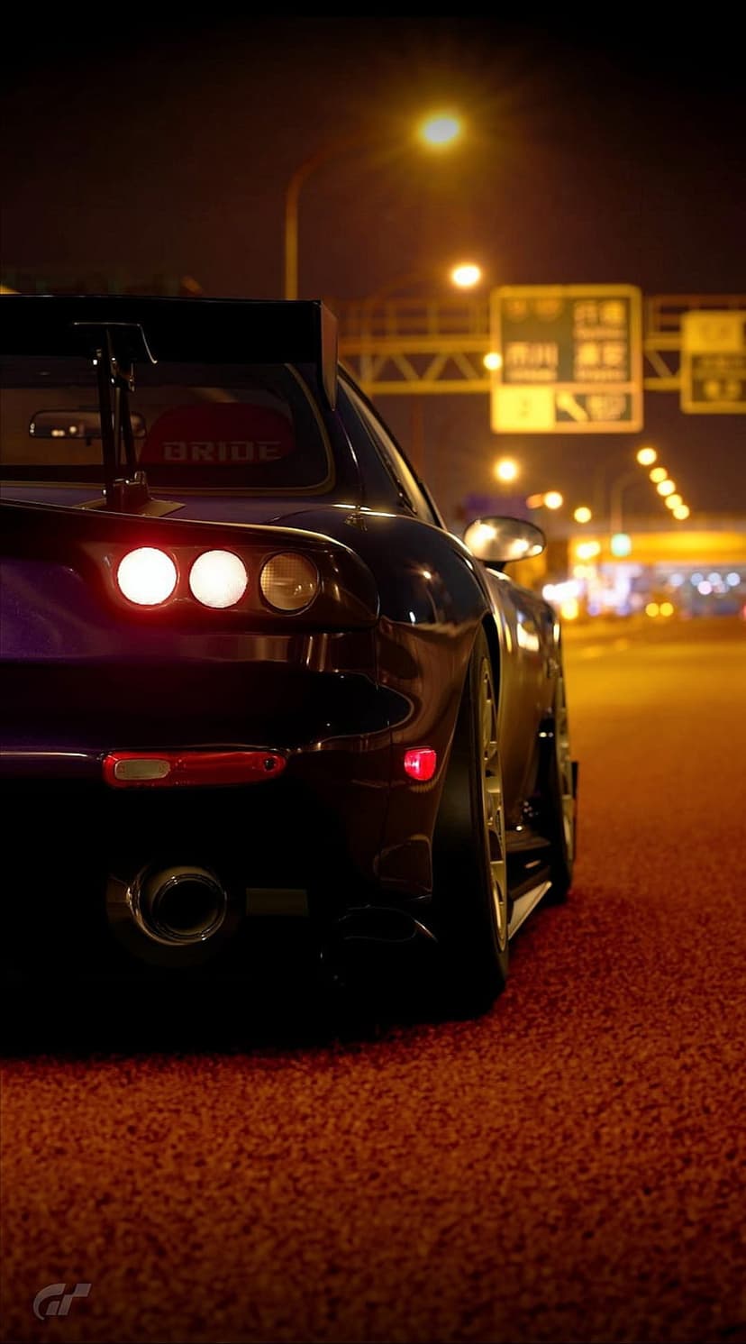 Dark purple Mazda RX-7 with glowing red taillights parked on a wet city street at night with urban lights.