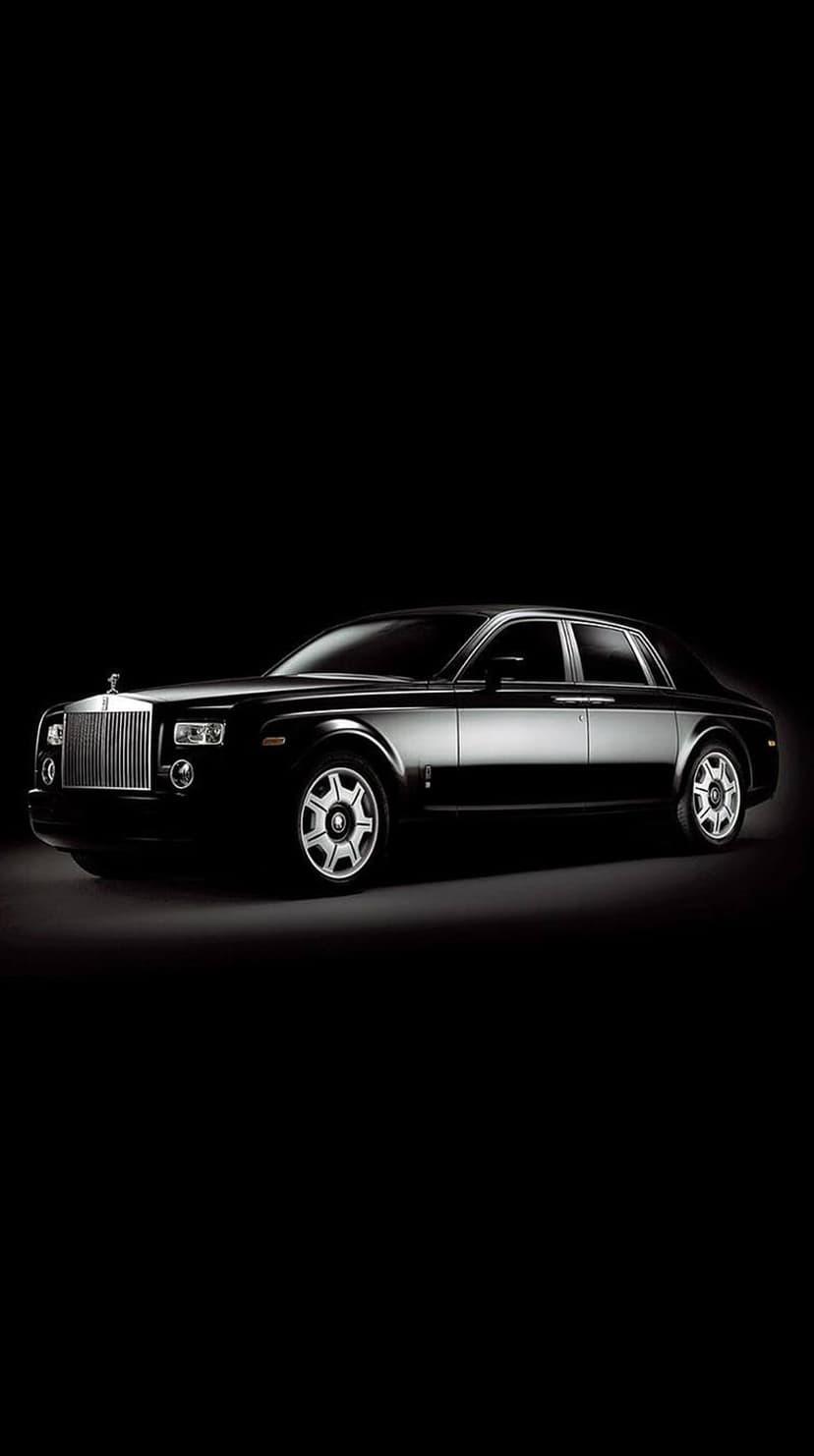 Rolls-Royce Phantom sedan with a glowing grille and chrome accents against a solid black background.