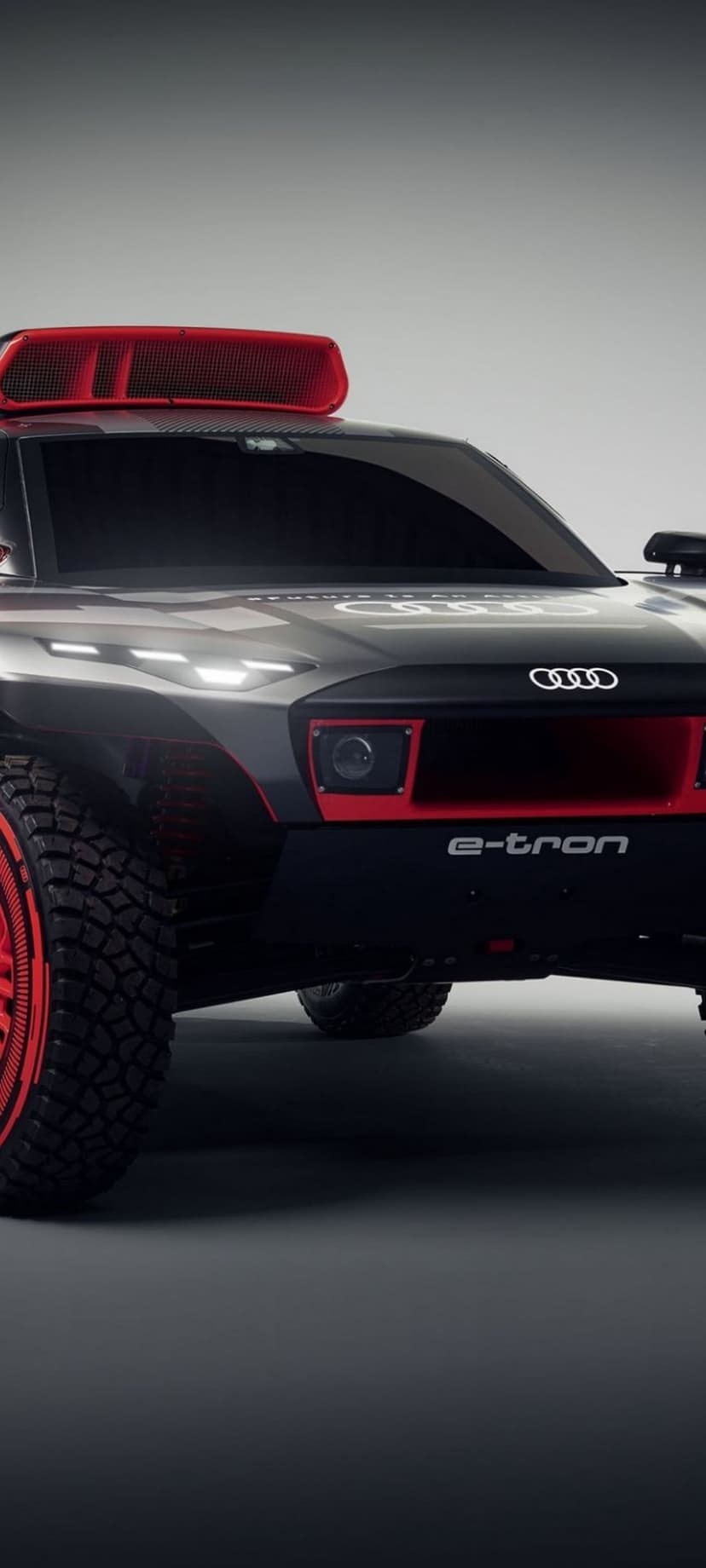 Audi RS Q E-tron rally car with glowing red LED lights and oversized off-road tires in a desert racing stance.