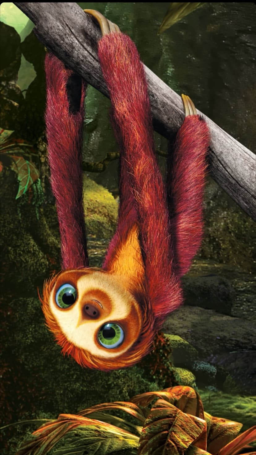 Sloth with vibrant green eyes and red fur hangs from a branch in a sun-dappled forest with lush green foliage.