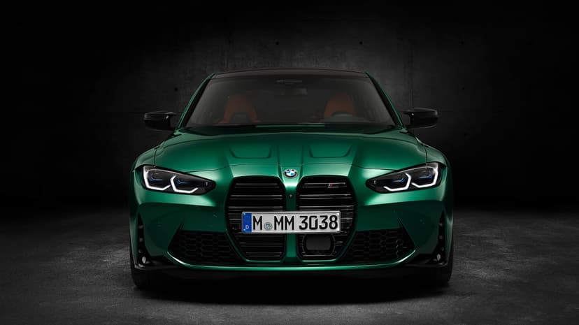 Front view of an Isle of Man Green BMW M3 Competition with glowing laser headlights in a dark textured studio.