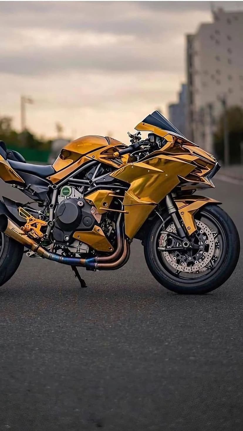 Gold custom motorcycle stands on asphalt with a reflective metallic finish against a blurred urban background.