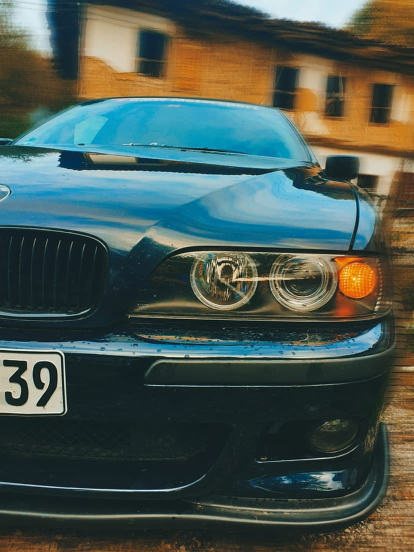 BMW E39 front end featuring illuminated angel eye headlights and a kidney grille against a blurred brick wall.
