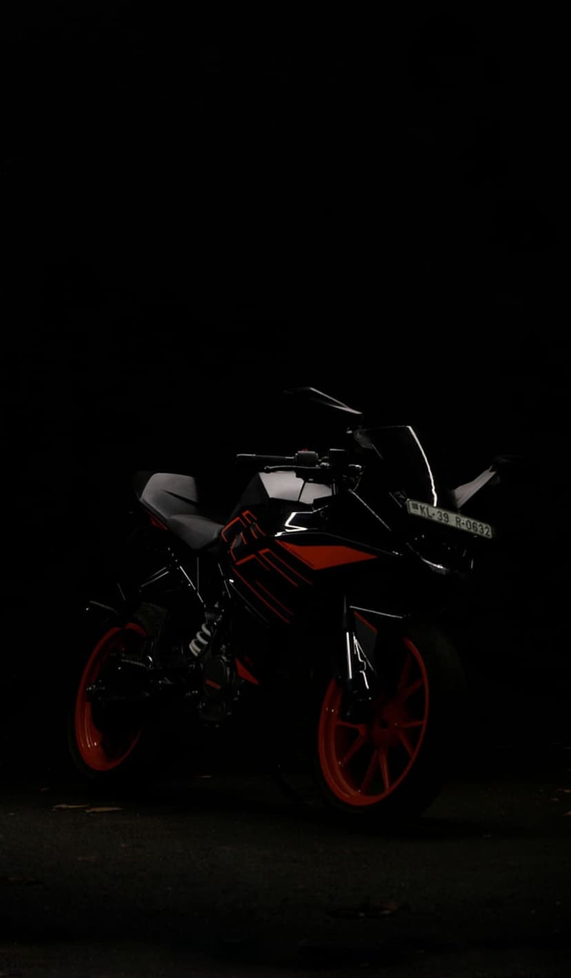 KTM RC sportbike with vibrant orange rims and frame accents sits in profile against a dark, minimalist background.