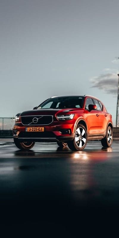 Red Volvo XC40 on wet pavement at sunset
