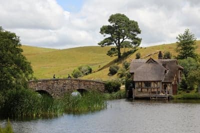 Hobbiton movie set with thatched cottage and stone bridge