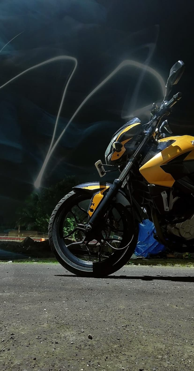 Yellow sportbike motorcycle with black accents surrounded by swirling white and yellow light trails at night.