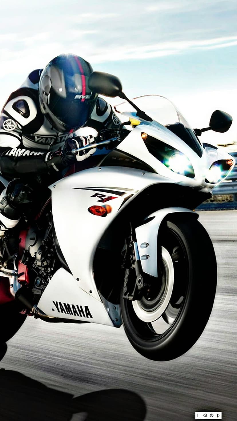 Yamaha R1 motorcycle rider leaning into a track turn with motion blur on the wheels under a bright clear sky.