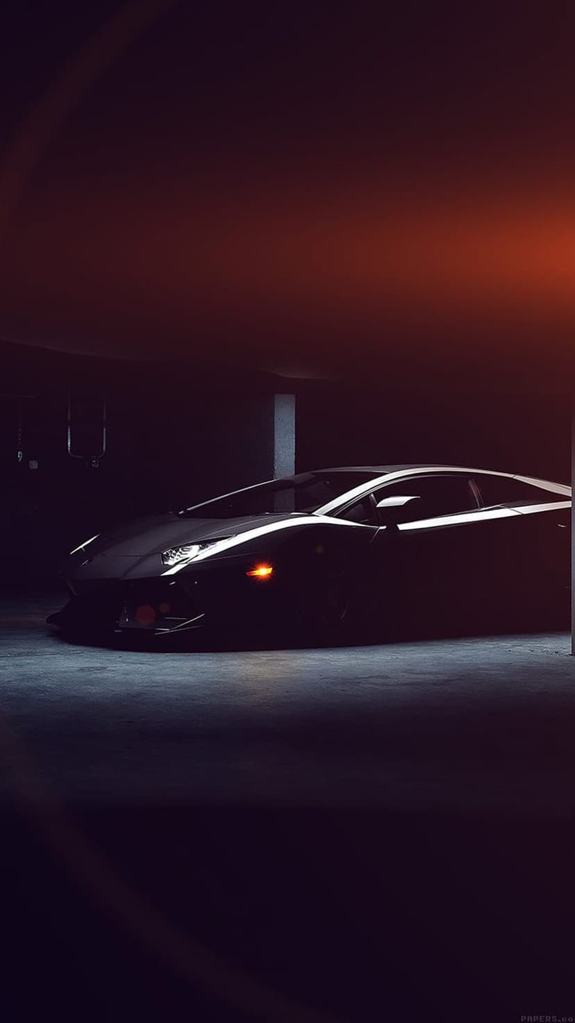 Black Lamborghini sports car parked in a dark garage with dramatic rim lighting on its sharp aerodynamic body.
