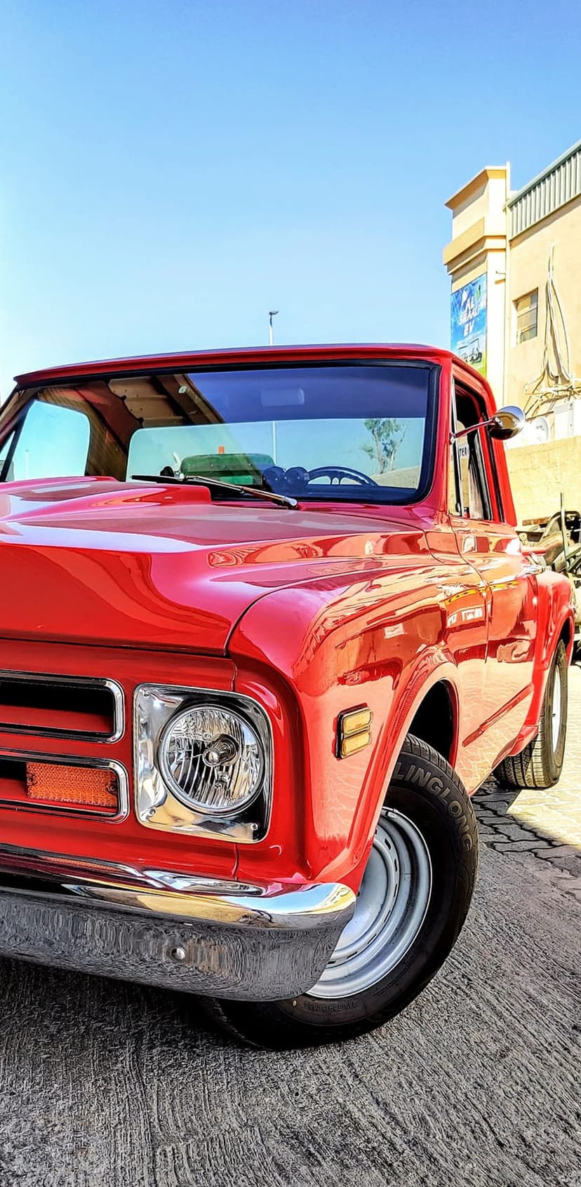 Red Chevrolet C10 pickup truck with a polished chrome bumper and round headlights viewed from a low angle.