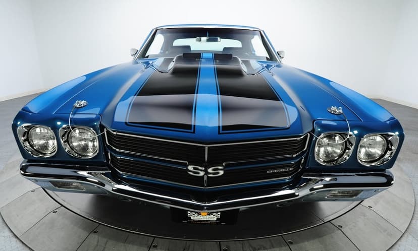 Front view of a blue 1970 Chevrolet Chevelle SS with black hood stripes and chrome bumpers in a white studio setting.