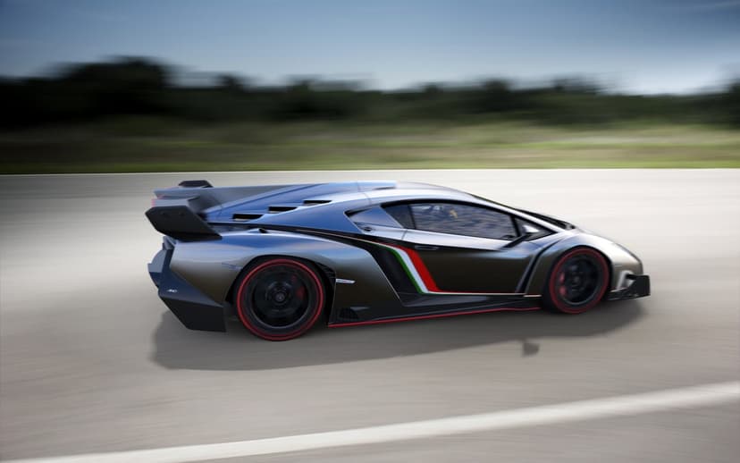 Lamborghini Veneno hypercar with red accents and Italian flag stripes speeding on a track with motion blur.