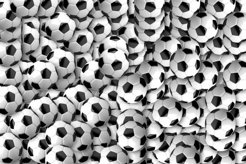 Soccer balls in a dense pile display black pentagonal and white hexagonal panels from a top-down perspective.